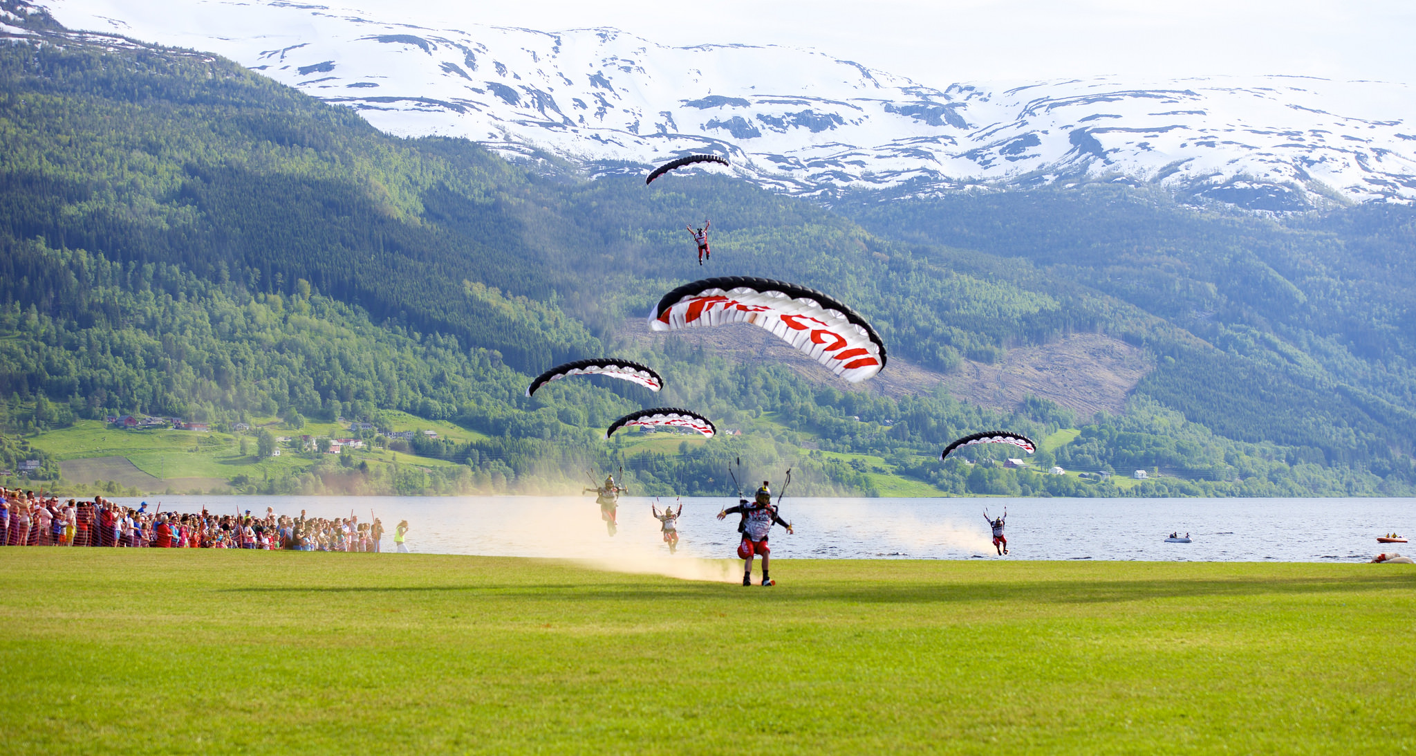Fem fallskjermhopparar landar ved folkemengdene under opningsshowet til Veko.