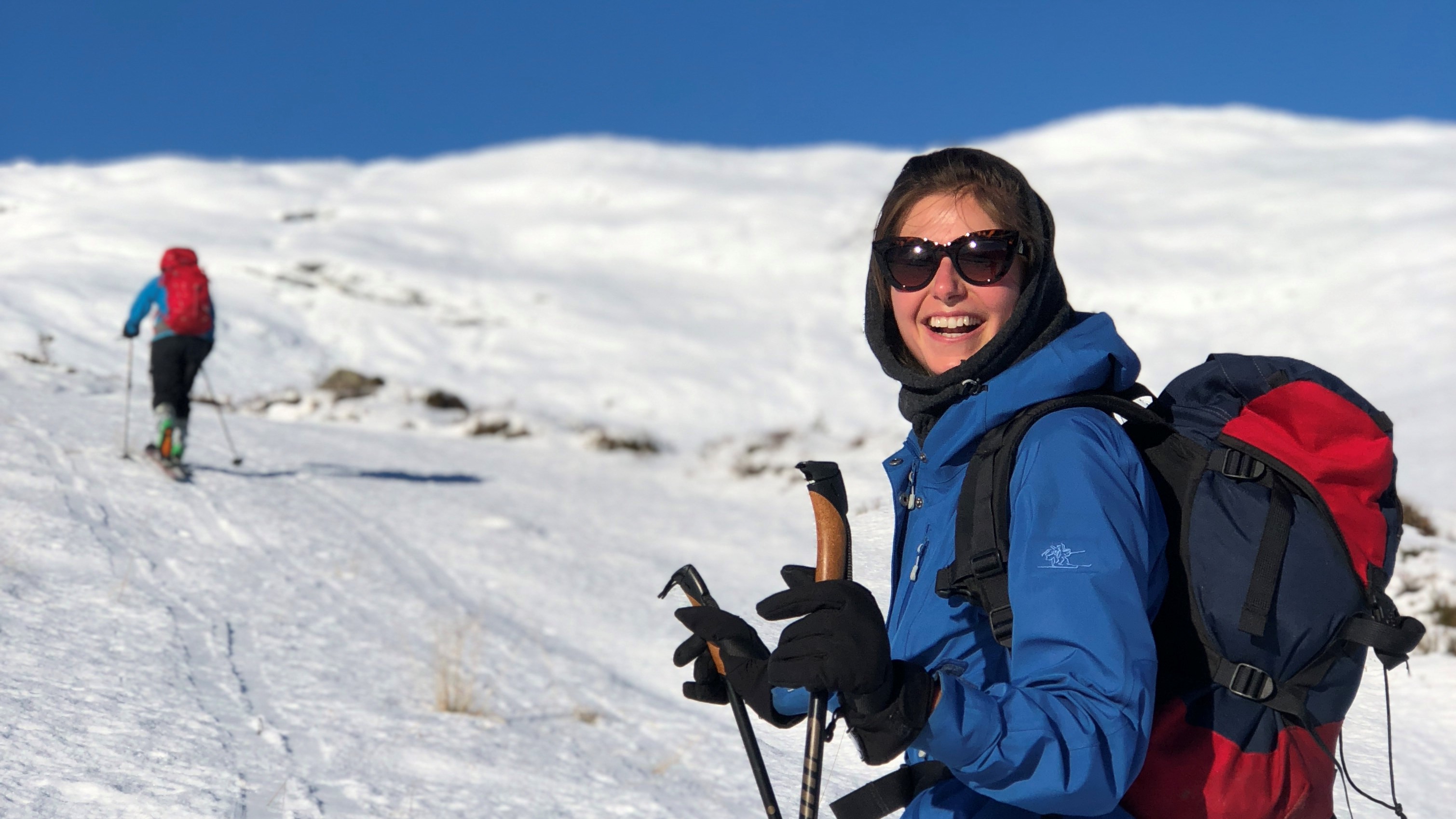 dame på ski smiler til kamera, på veg til toppen