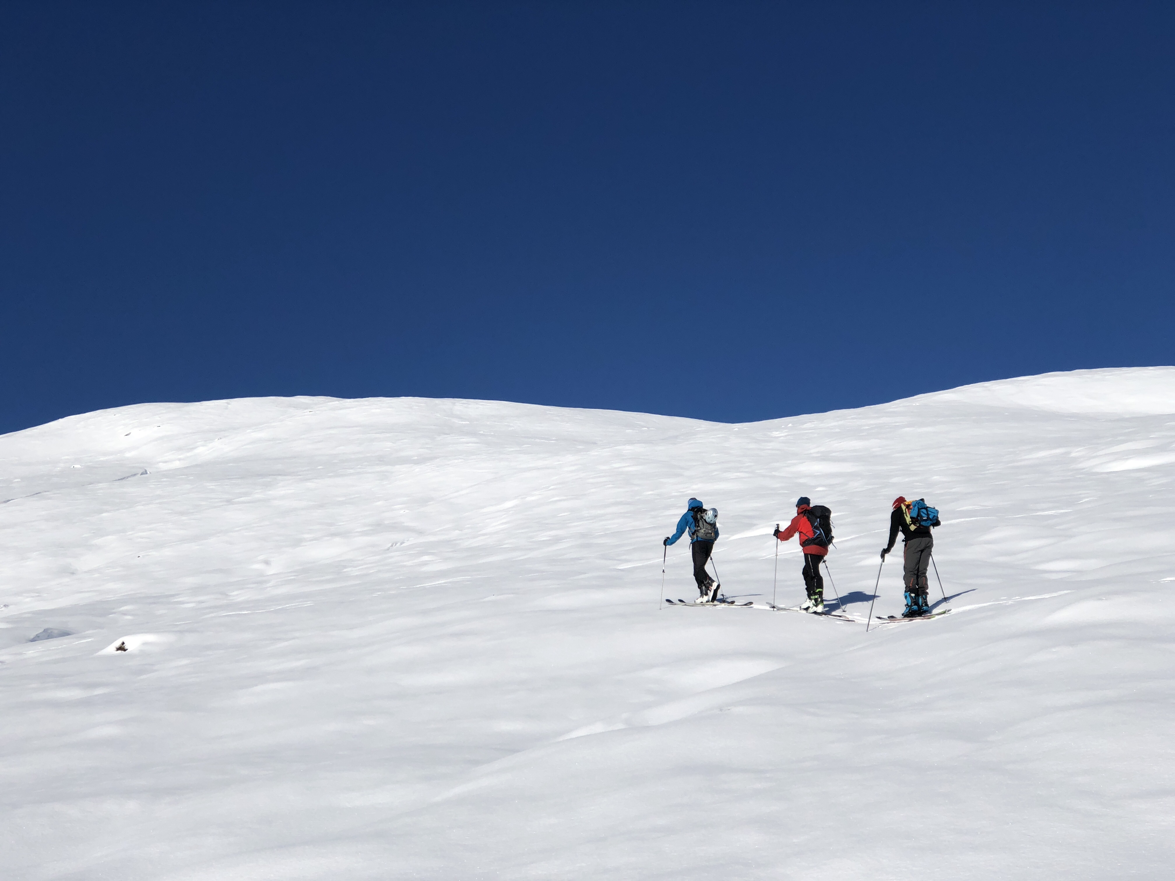 folk på vei oppover en fjellside, på randoneeski