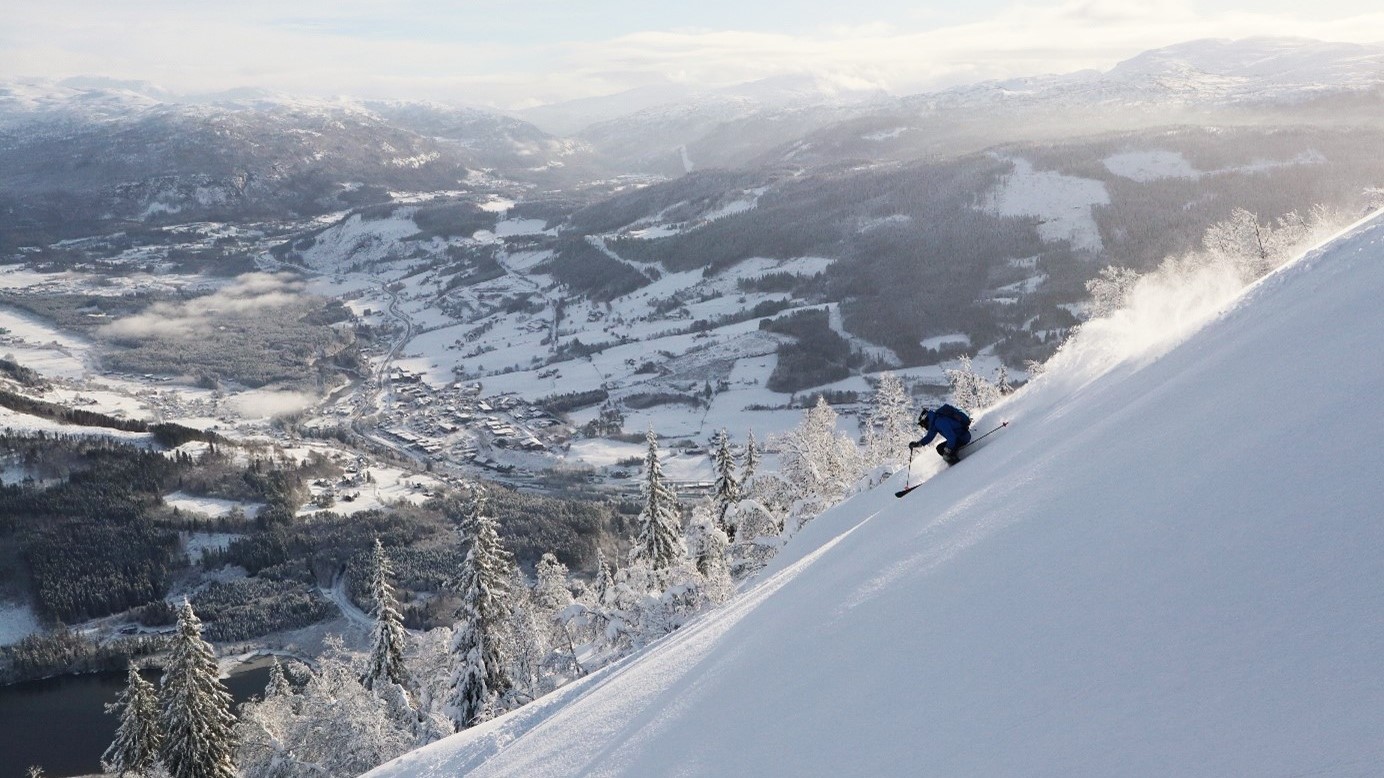 mann på ski i voss resort, bebyggelsen like i bakgrunnen