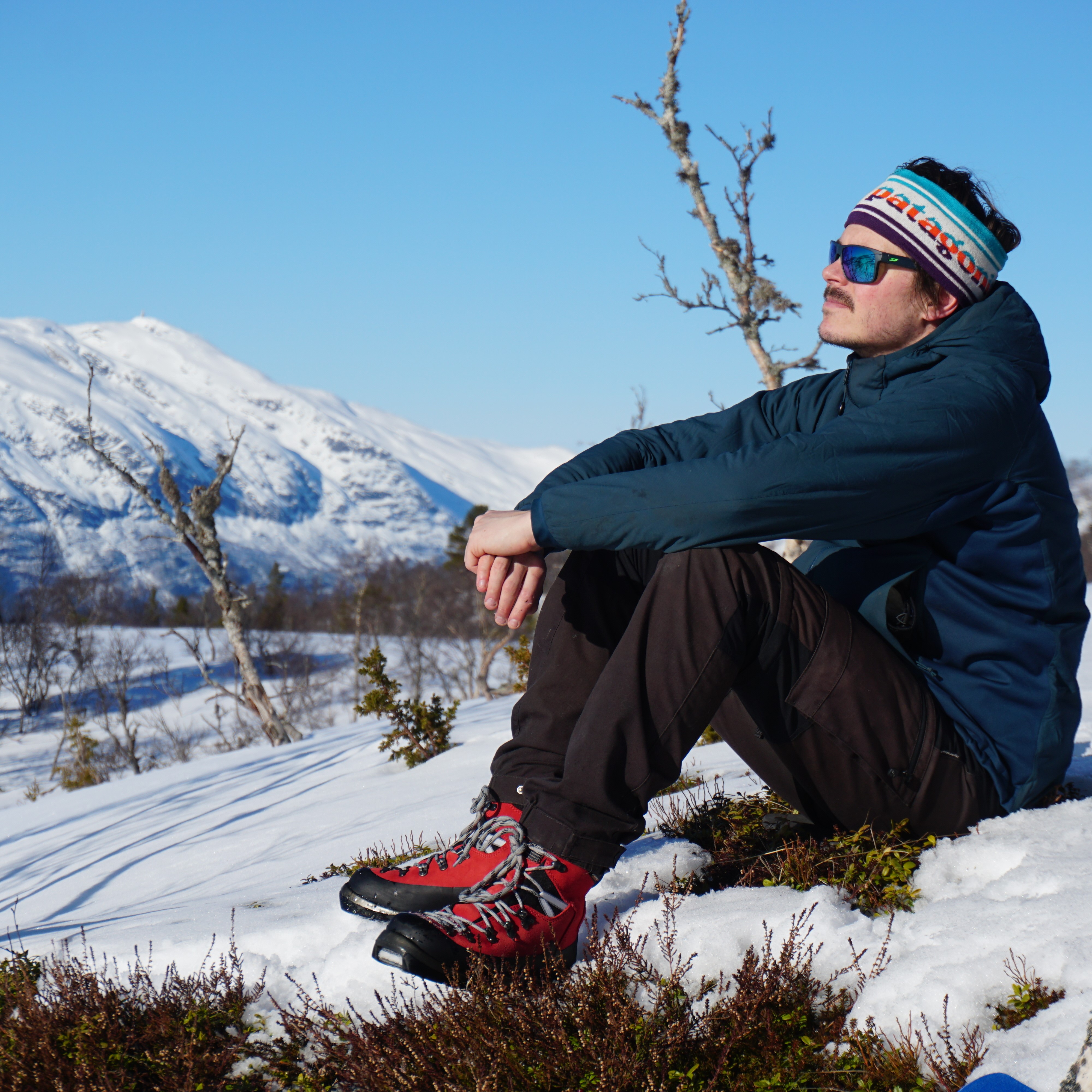mann tar en pause i skituren, i solen på fjellet