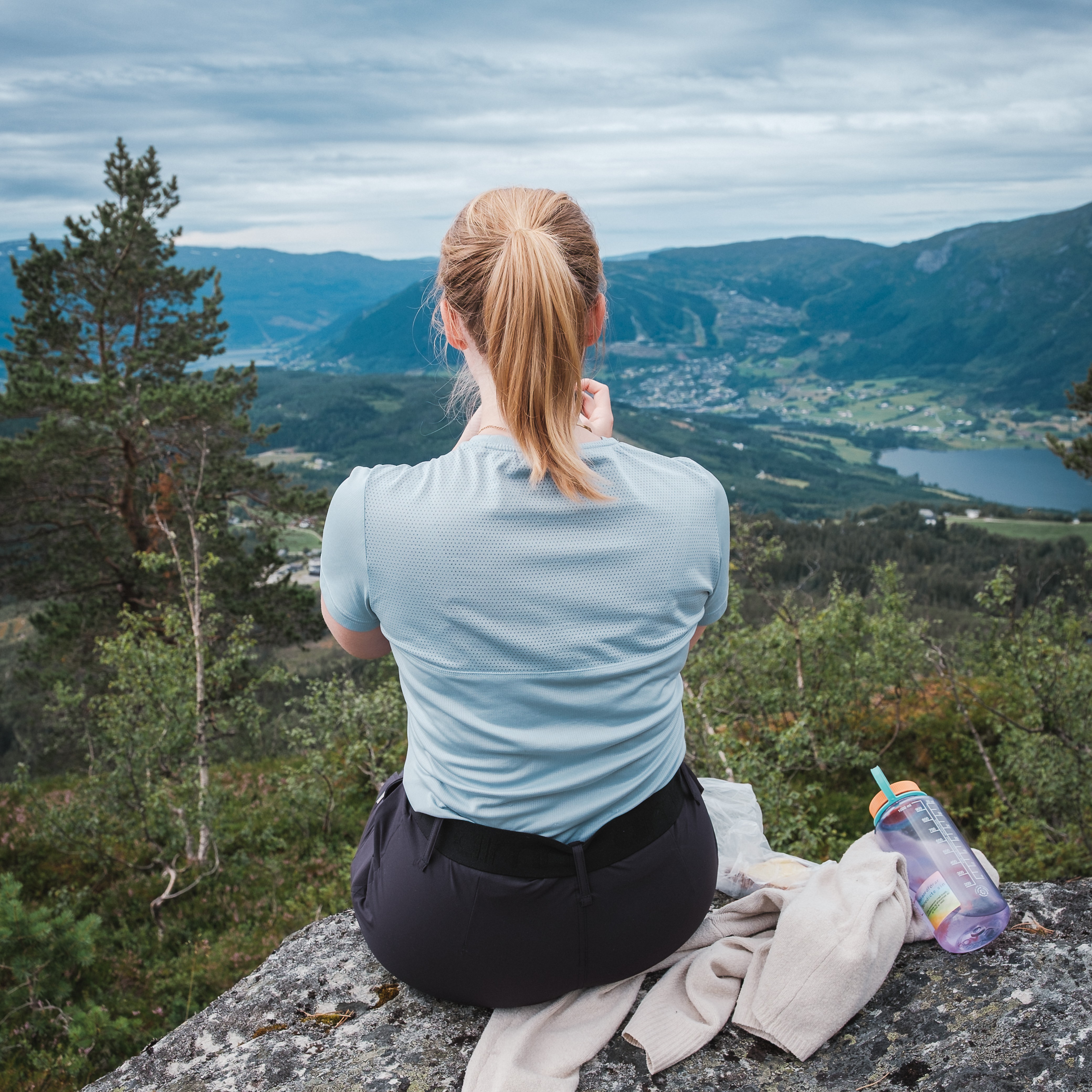 en kvinne står nært kamera med ryggen til og ser på utsikten over lønavatnet og bavallen, i Voss herad