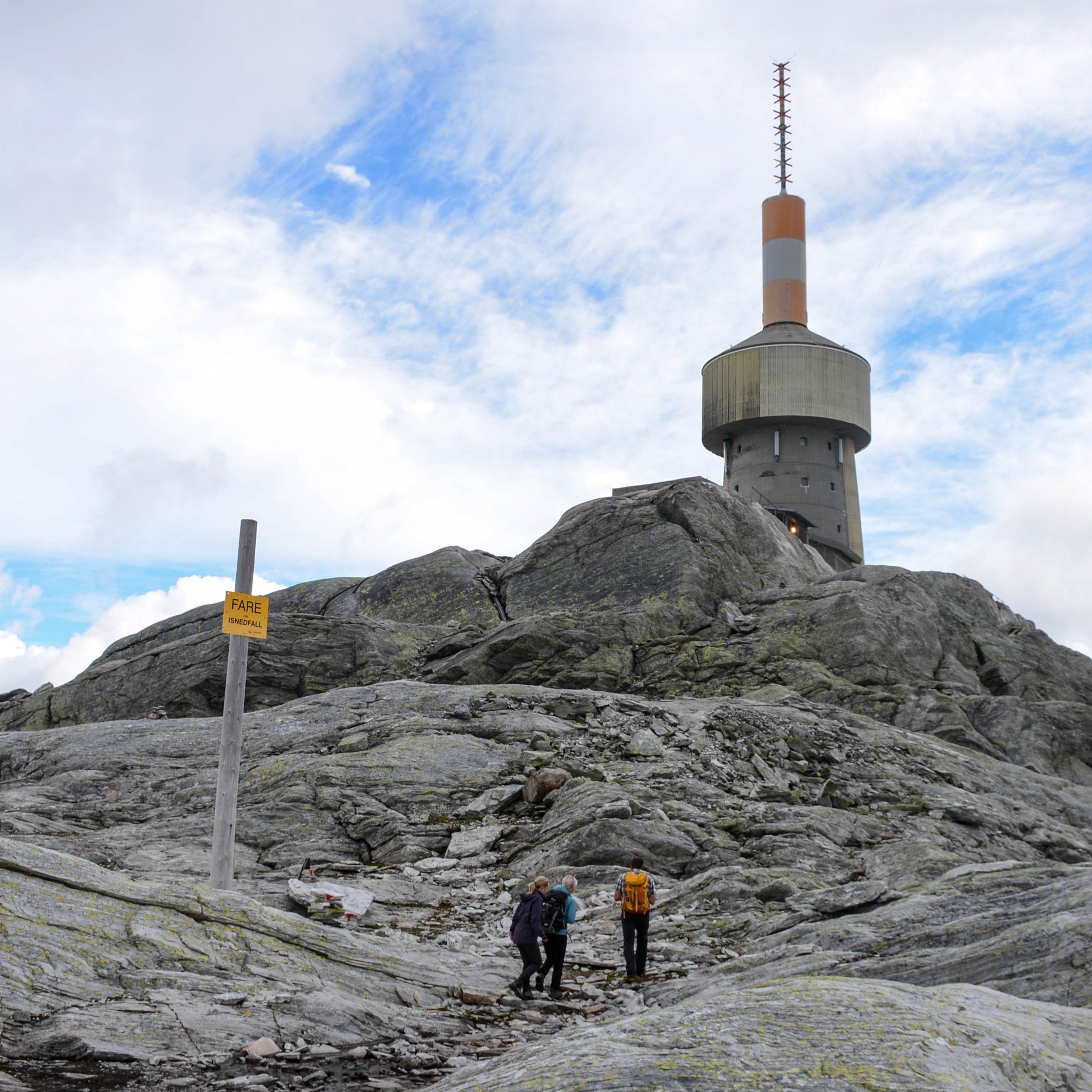 Tre personar er nesten på toppen av Lønahorgi, ved masta som ein kan sjå frå lang avstand