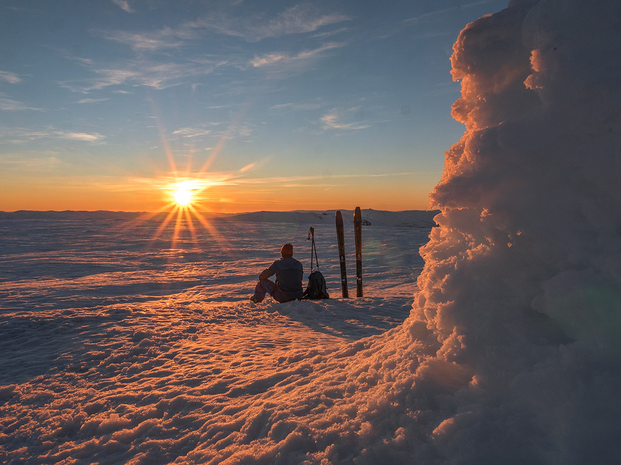 mann sitter på toppen av olsskavlen på voss, i kveldssol