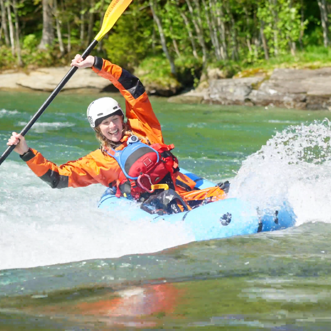 dame som surfer en bølge i packraft, på voss