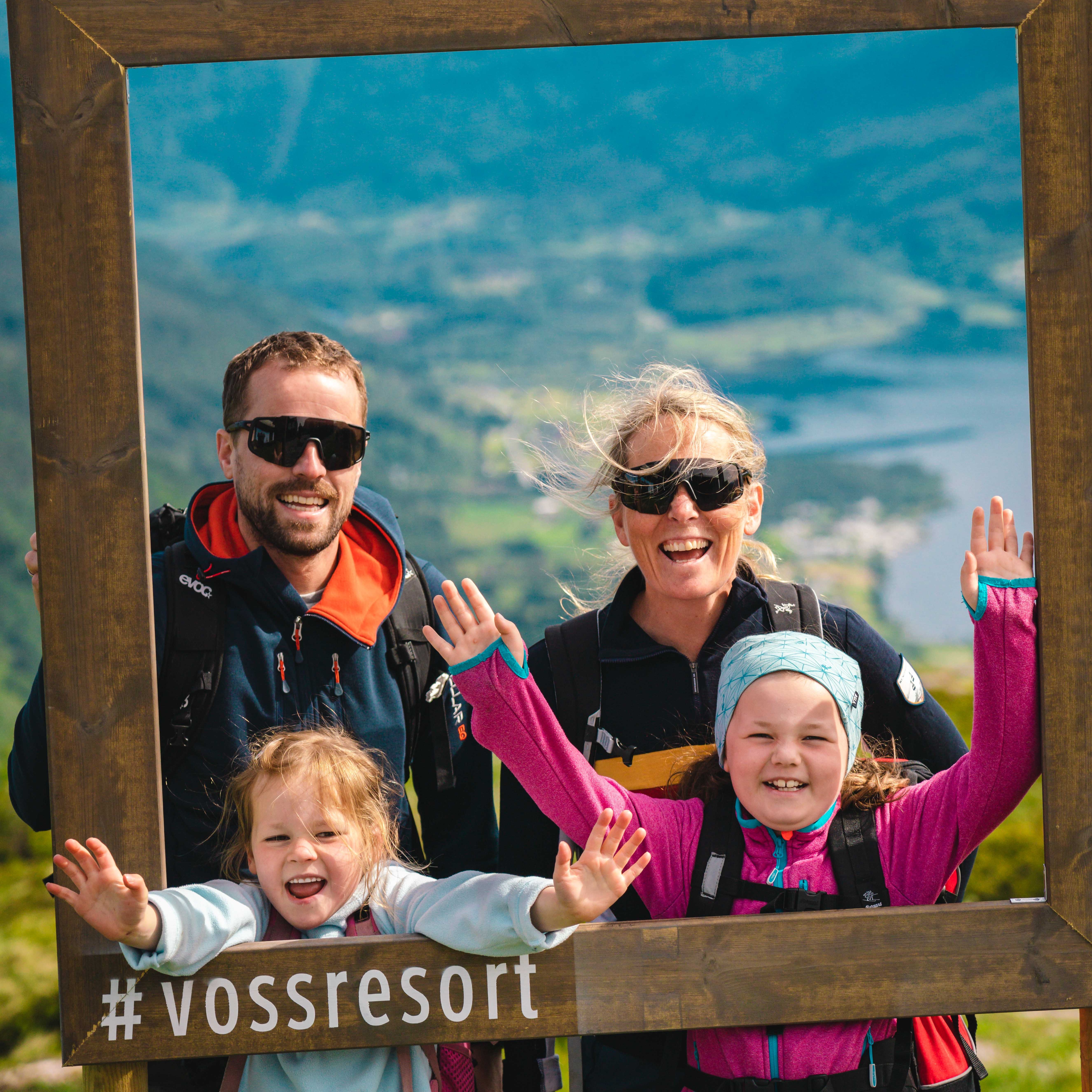 familie på tur, på Hangurstoppen. Poserer i ramme med teksten "Voss Resort".