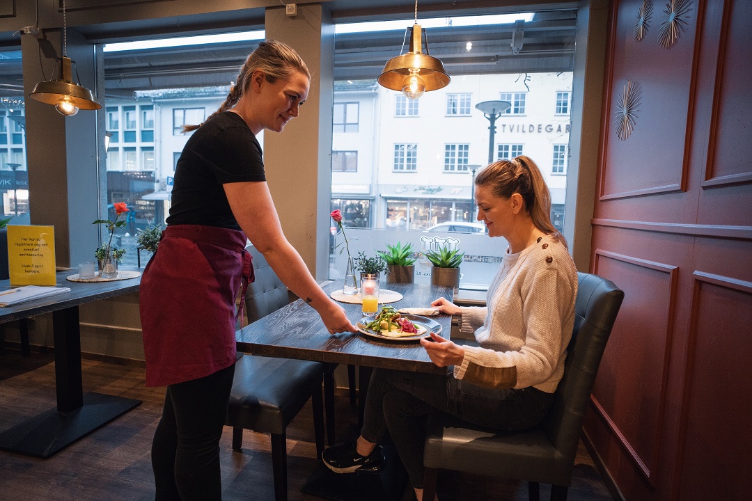 dame får servert middag på ringheim cafe av smilende servitør