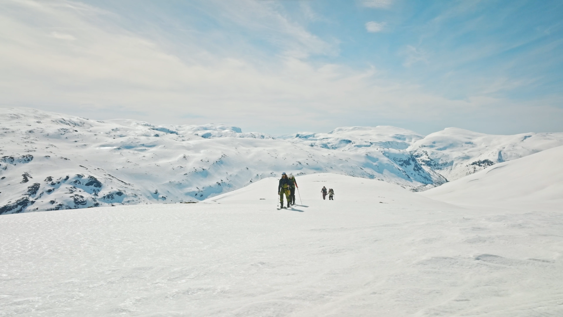 fire personer på vei til en snødekt fjelltopp