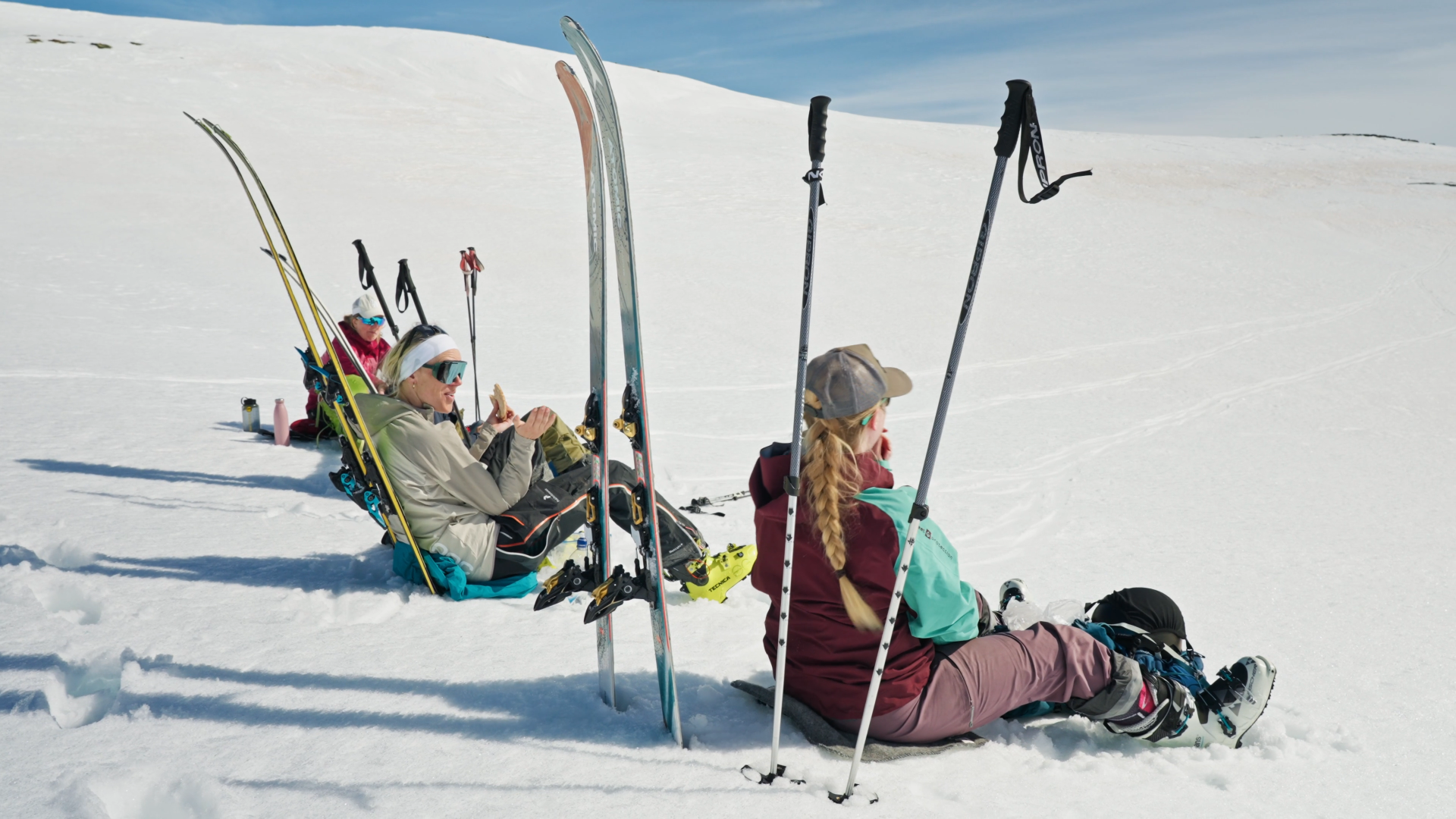 fire personer tar en pause på skituren, og slapper av i solen 