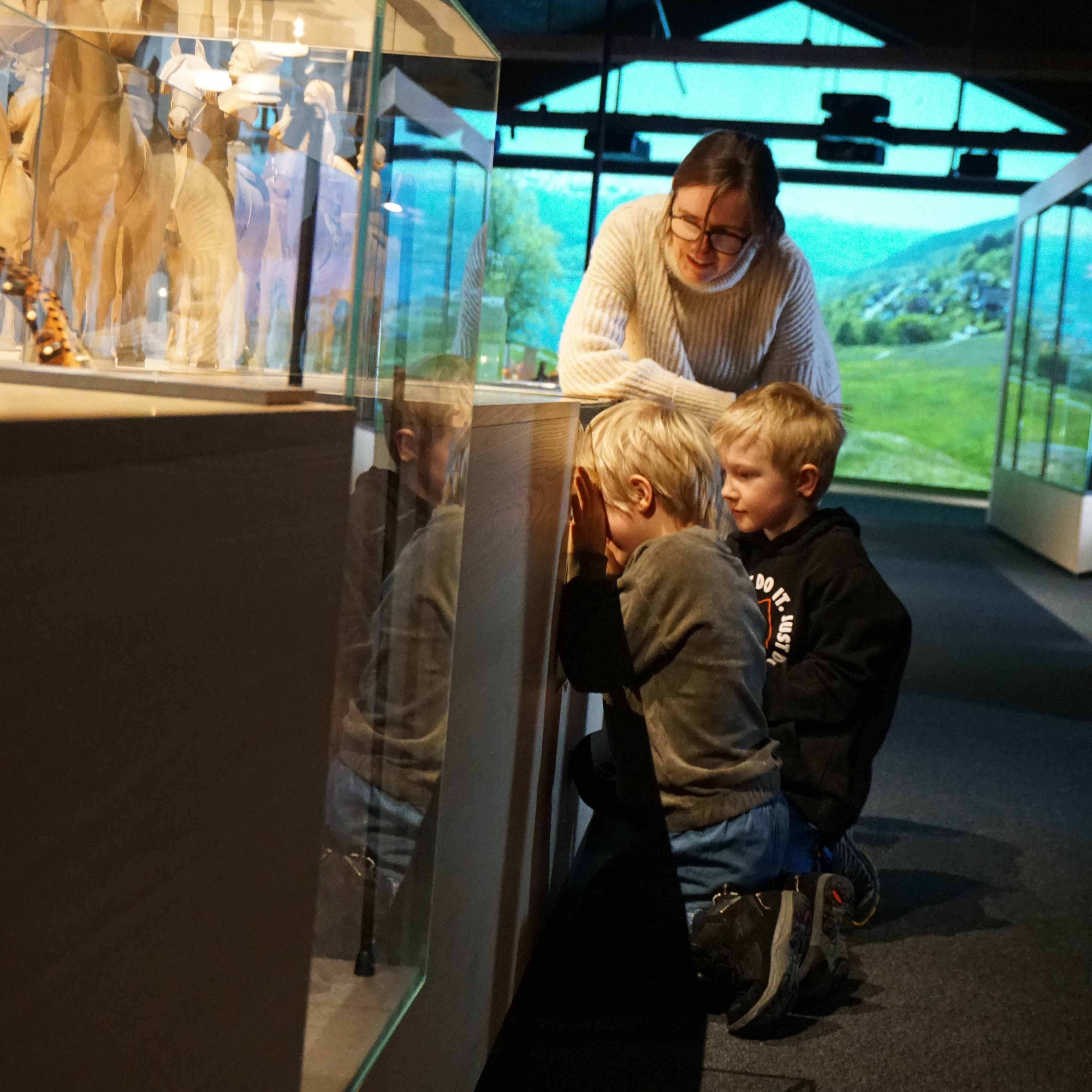 to barn ser på utstillingen til voss folkemuseum, sammen med en ansatt. 