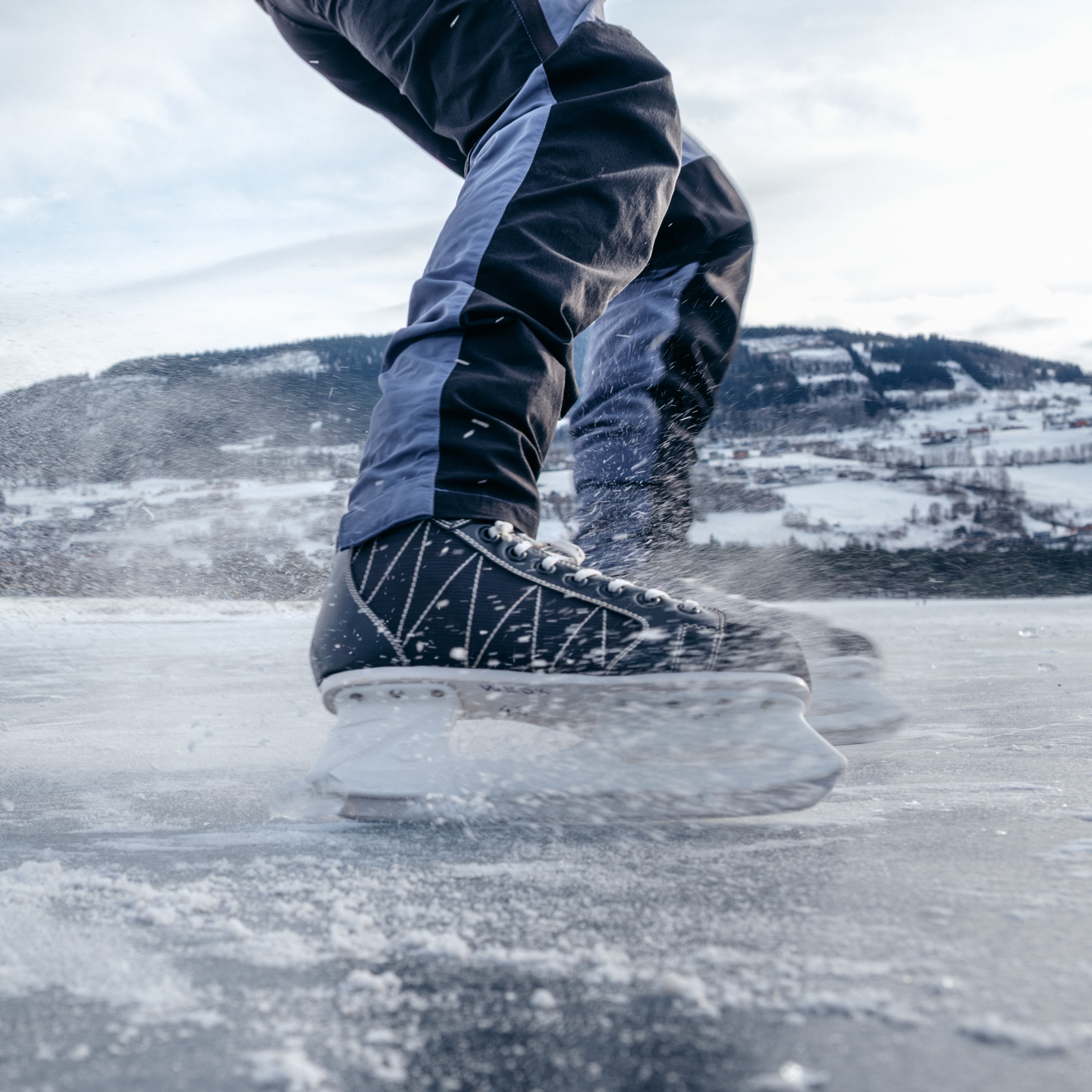 nærbilde av skøyter som skrenser på isen, mot kamera.