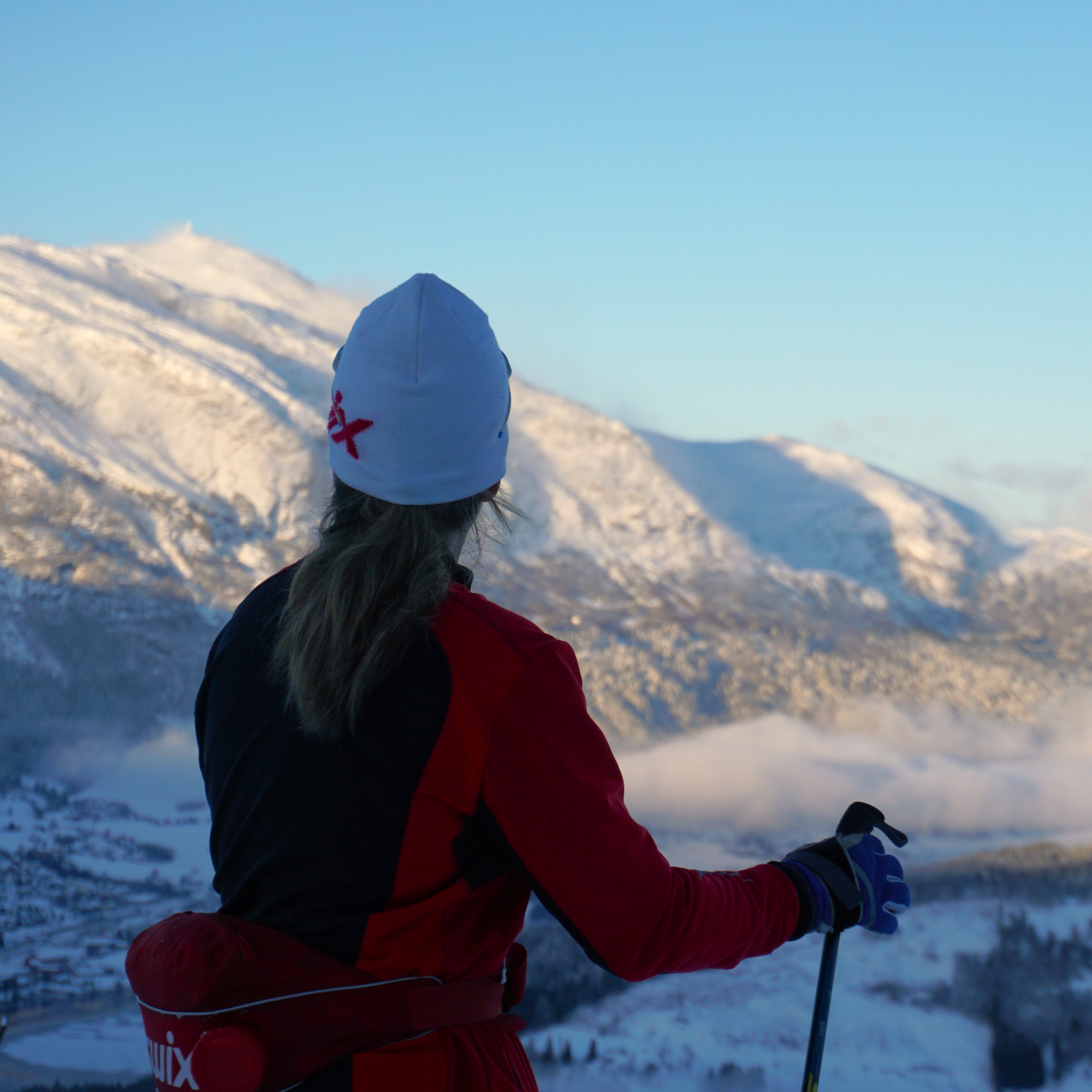foto av ei kvinne på ski, som nyter utsikter over dei snøkledde fjella på voss. Utsikten er frå Voss ski og tursenter. 