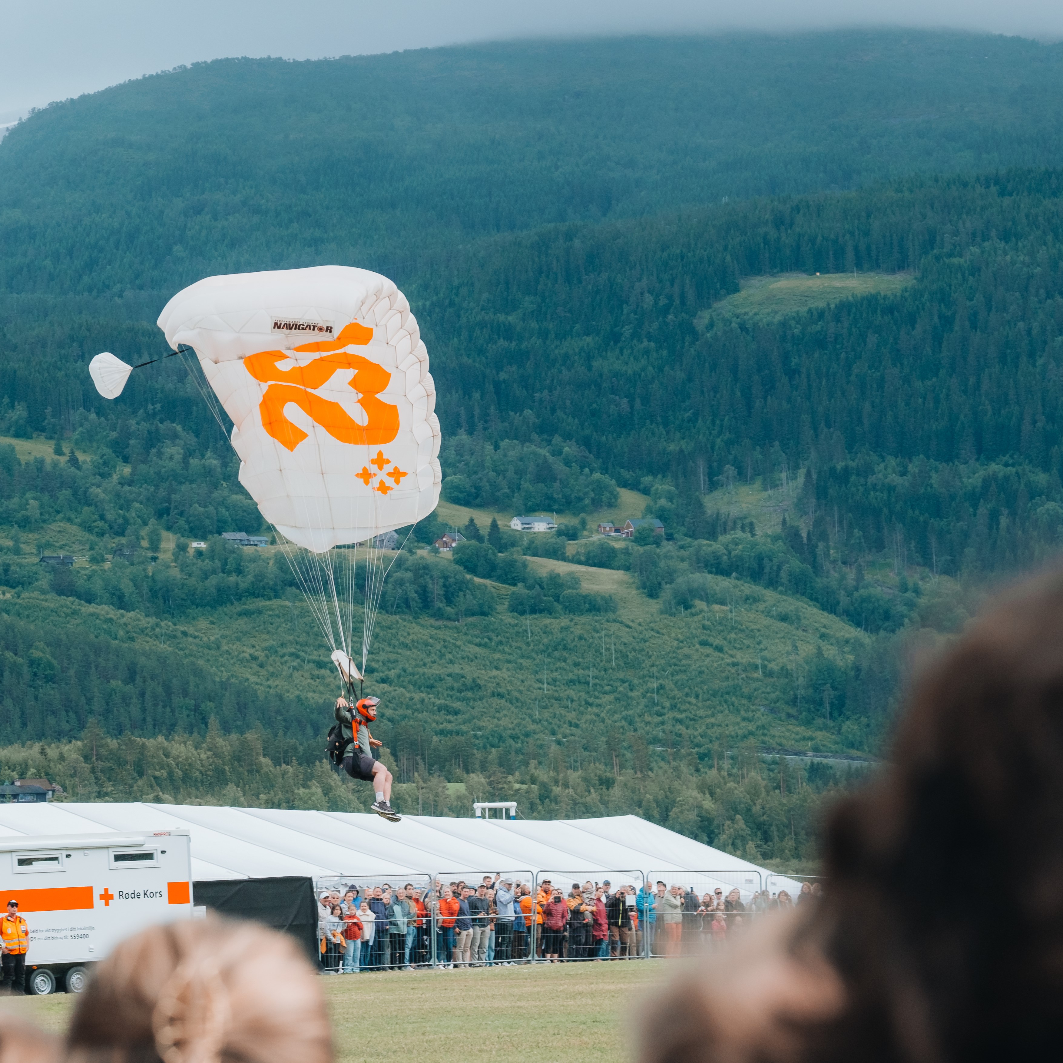 opningsshow på veko. Publikum ser på fallskjermhoppar som går inn for landing. 