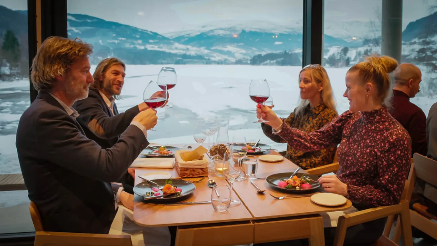 En gjen nyter middag på elva hotell, med utsikt over vatnet og fjella i den flotte restauranten