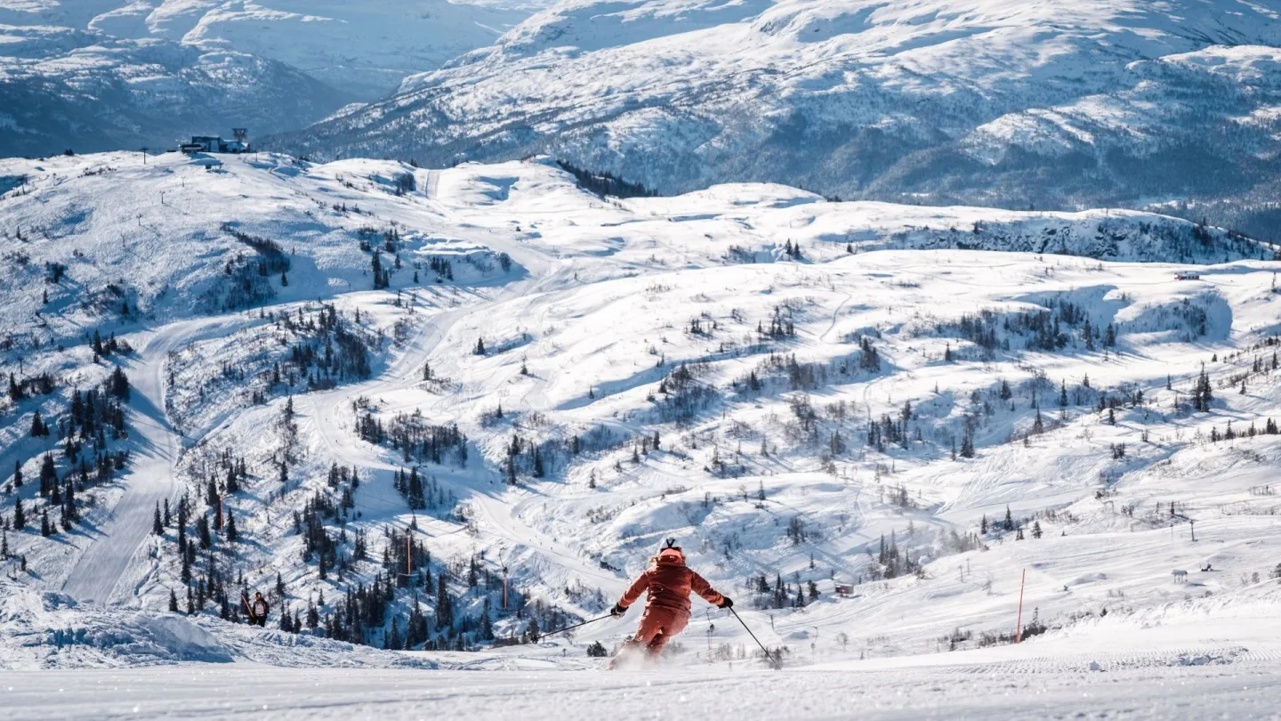 Kvinne på slalom, med flott utsikt over Voss Resort i vinterdrakt. 