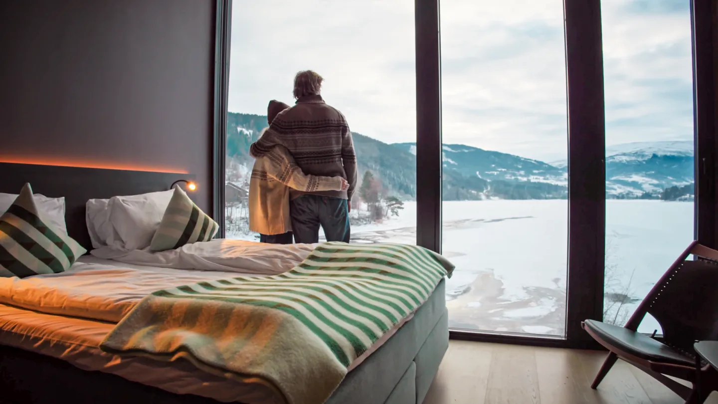 Par nyter utsikten frå rommet sitt på Elva hotel. Her ser ein utover vatnet og fjella på Voss