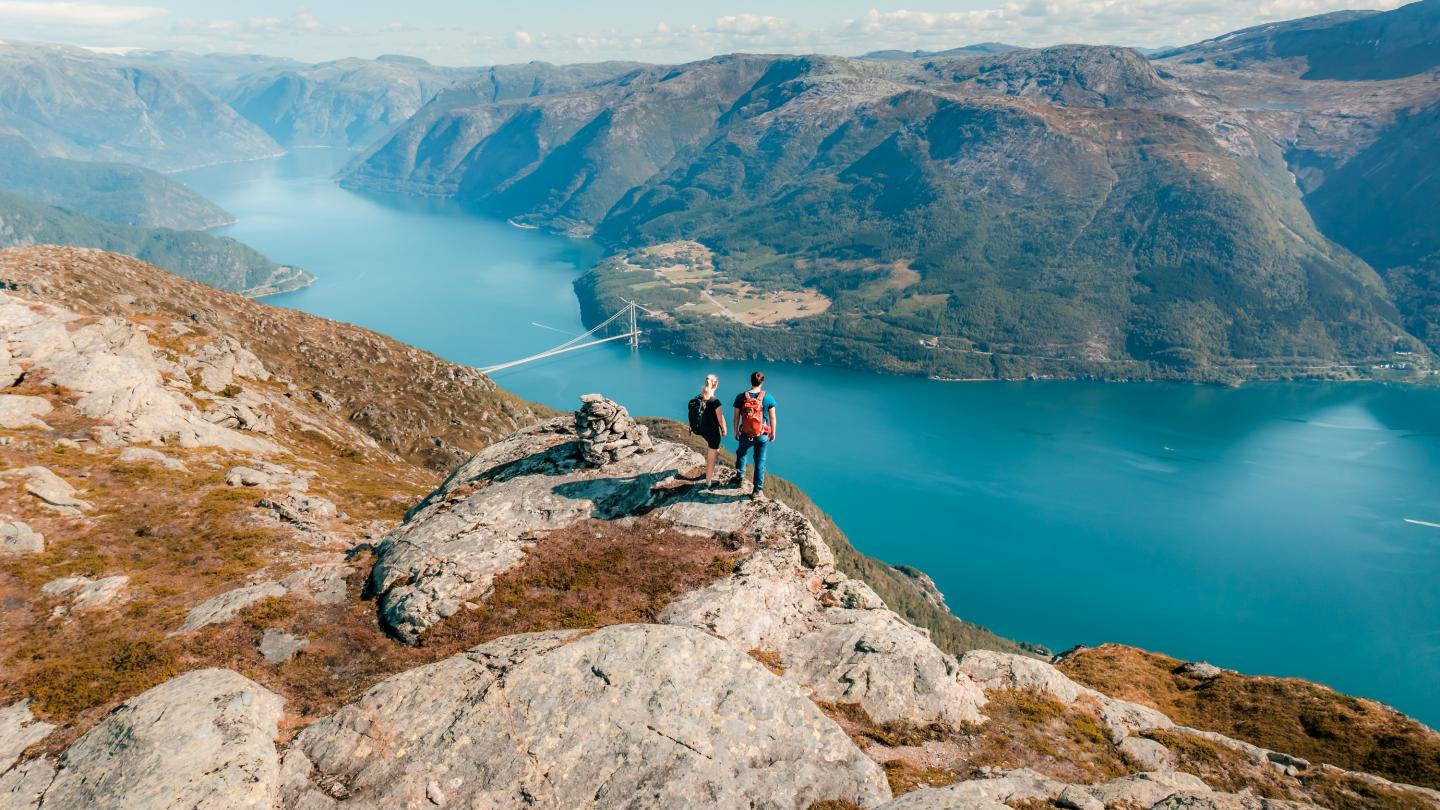 Par på toppen av ingebjørgfjellet, hardangerbura og hardangerfjorden i bakgrunnen