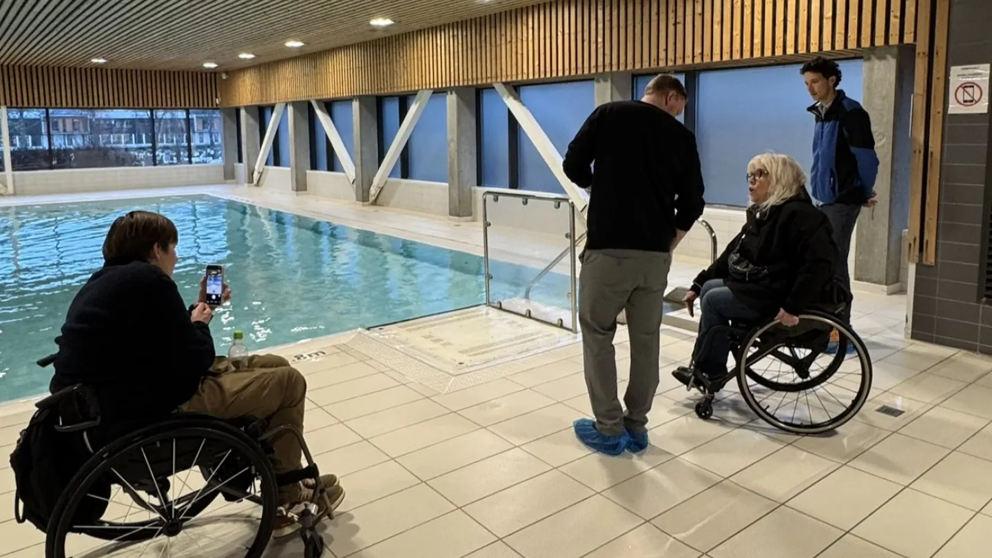 Fire voksne ser på rullestolheisen i Vossabadet