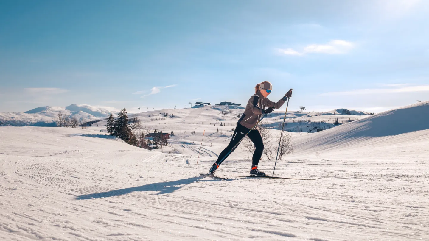 Kvinne på langrenn, på fjellet, i sol