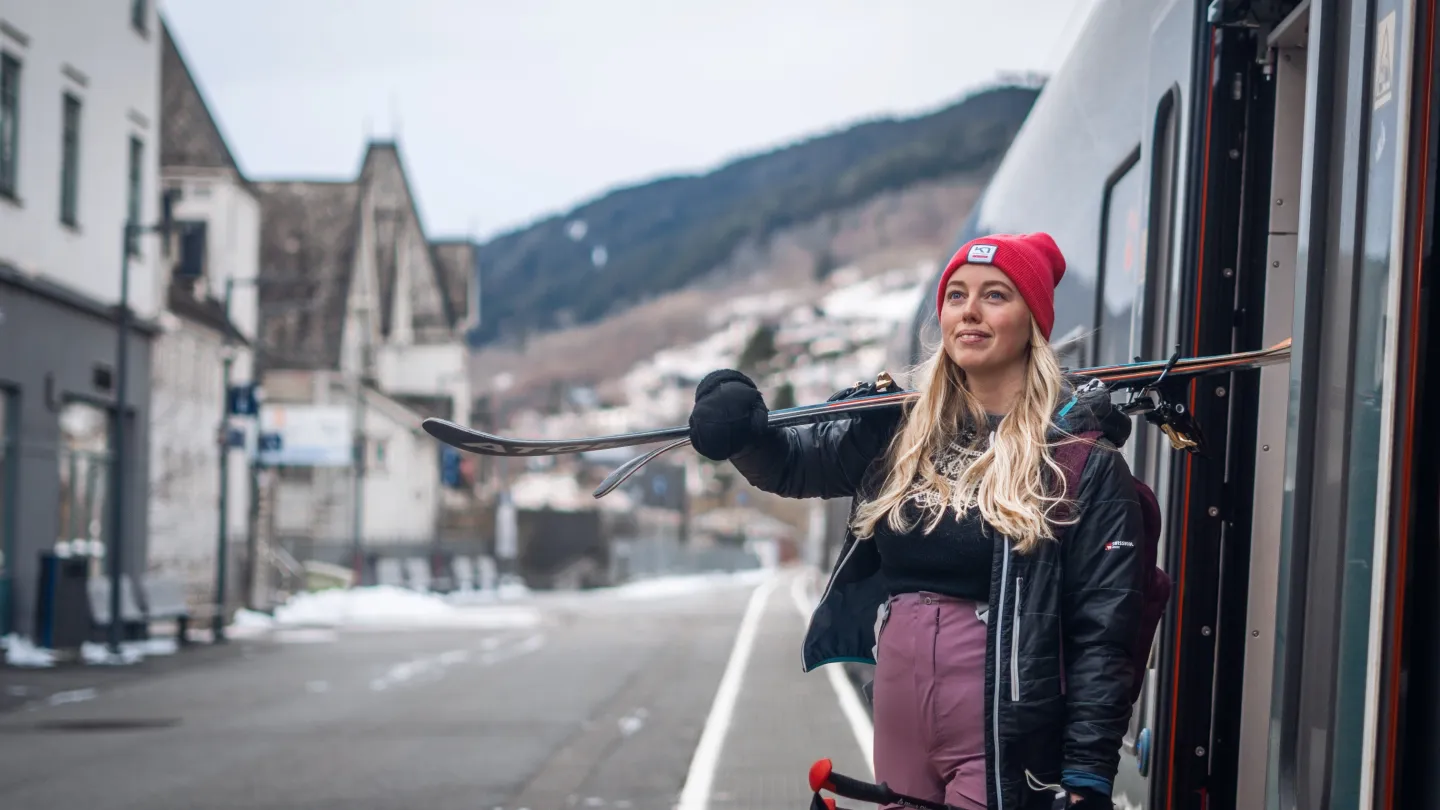 kvinne går av toget, på voss stasjon, med ski på skulderen