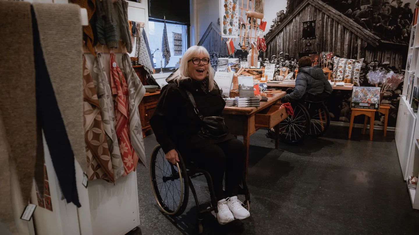 Dame i rullestol beveger seg lett rundt i suvenirbutikken hos Voss Folkemuseum